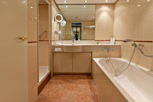 La salle de bains est pourvue d'une baignoire, d'un lavabo et d'une douche. dans l'établissement Landgoed De Wilmersberg, à De Lutte