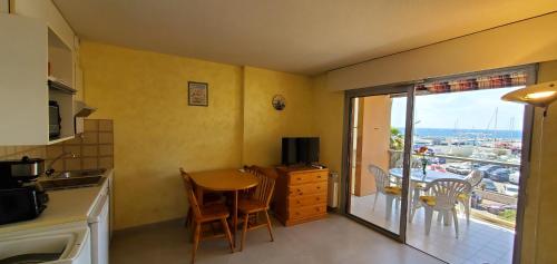 Il dispose d'un balcon et d'une cuisine avec une table et des chaises. dans l'établissement LE CAPITOLE Vue mer Studio cabine 27m2 2 adultes 2 enfants avec climatisation et garage, à Fréjus