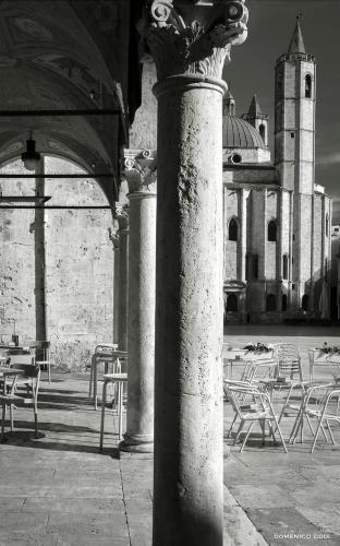 a column in front of a building with tables and chairs at Nella Torre Bed & Breakfast in Ascoli Piceno