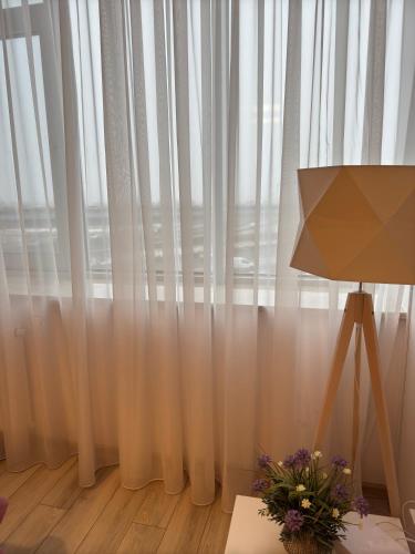 a room with a window with white curtains and a lamp at Zlatarooms in Warsaw