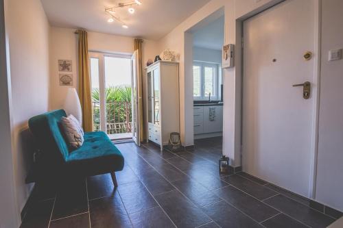 a living room with a blue chair and a balcony at Violet Seaview Apartment in Vis