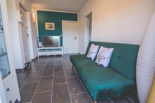 a living room with a green couch and a television at Violet Seaview Apartment in Vis