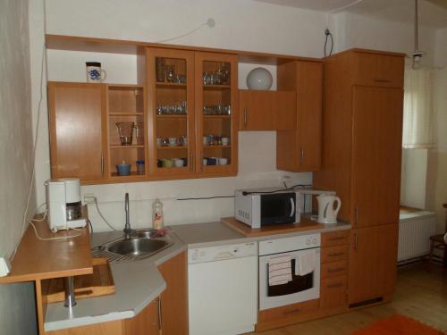 a kitchen with wooden cabinets and a microwave at Turistická ubytovna Podomí in Podomí