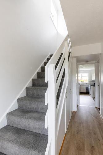 a staircase in a house with white walls and wood floors at The Conifers large detached home with off street parking in Witney