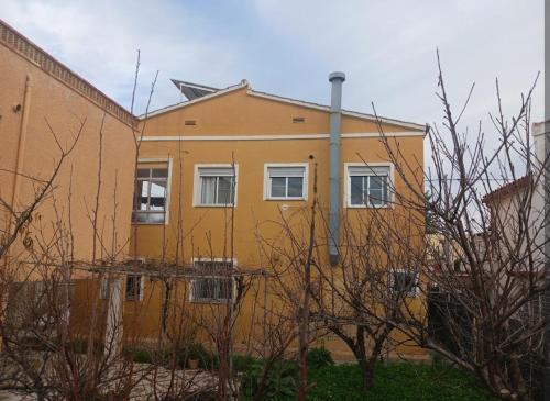 a yellow building with white windows on the side of it at Casa a 200 metros de la playa 10 PAX in Almazora