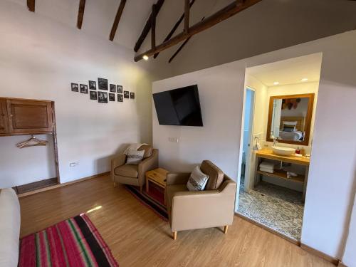 a living room with two chairs and a television at CASA CRISTOBAL Siete Cuartones in Cusco