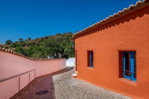 an orange building with two windows and a wall at Alte Com Amor in Alte