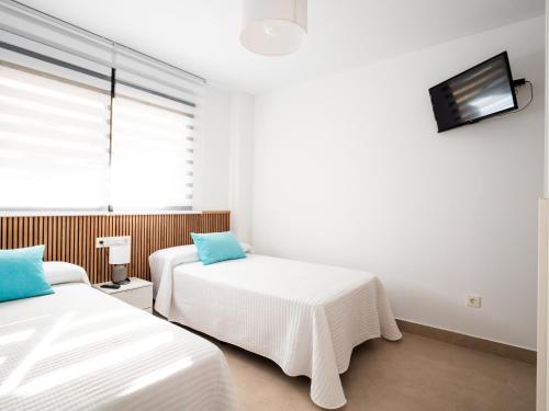 two beds in a room with a tv on the wall at 'Mi Esperanza' in Almuñécar