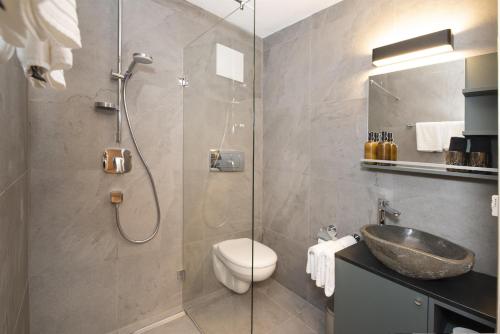a bathroom with a shower with a sink and a toilet at Natural Deluxe Apartments Alpbach in Alpbach