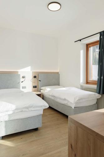 a bedroom with two beds and a window at Appartamenti Terme Viola in Pozza di Fassa