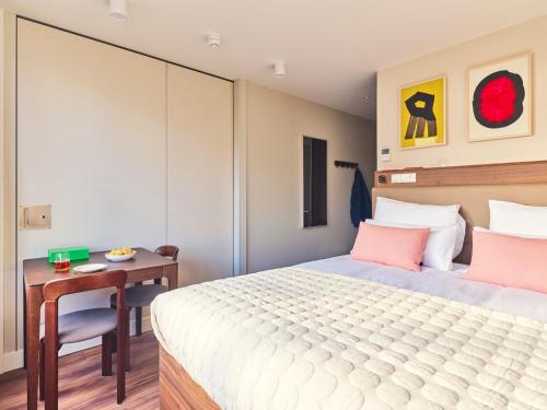 a bedroom with a bed and a table with a chair at Numa The Hague Scheveningen in Scheveningen
