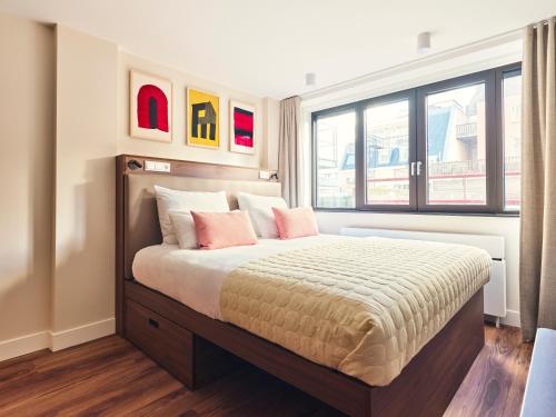 a bedroom with a large bed with pink pillows at Numa The Hague Scheveningen in Scheveningen