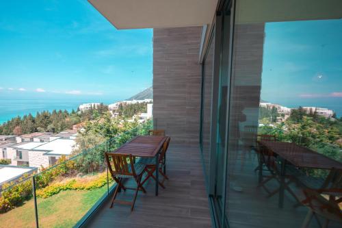 a balcony with tables and chairs and a view of the ocean at Escape by Form Apartament 3 in Dhërmi