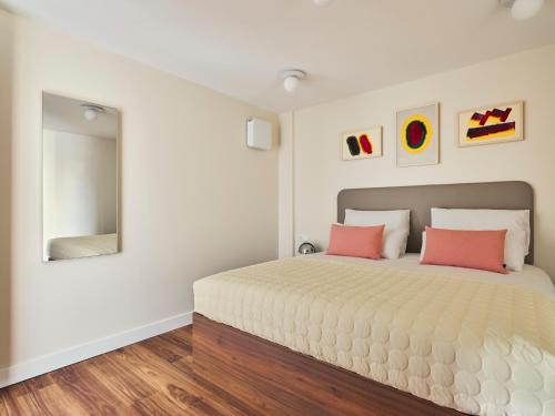 a bedroom with a large bed with two pink pillows at Numa The Hague Scheveningen in Scheveningen