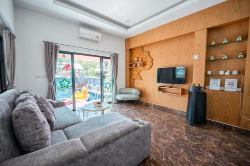 a living room with a couch and a tv at Baanmeesuk Pool Villa Pattaya in Jomtien Beach