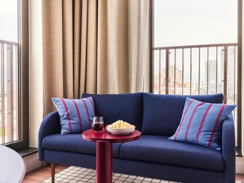a blue couch in a living room with a table at Numa The Hague Scheveningen in Scheveningen