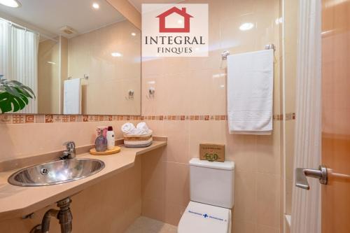 a bathroom with a sink and a toilet and a mirror at Blue Wave Apartment in Calonge