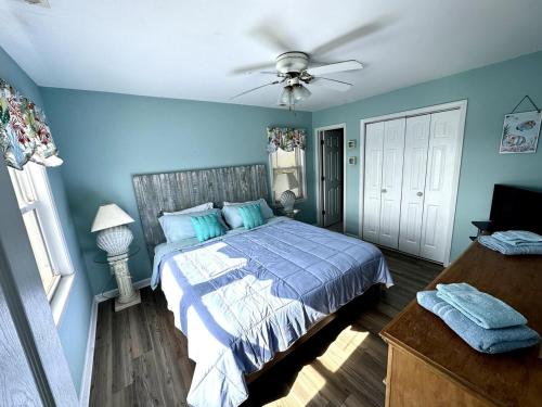 a blue bedroom with a bed and a ceiling fan at Beautiful beach and bayfront house in North Topsail Beach