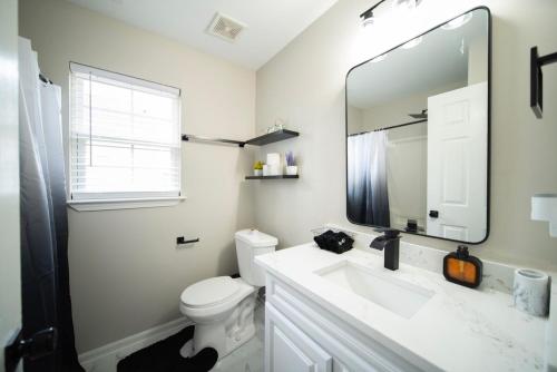 a white bathroom with a sink and a mirror at Raleigh With Daylor in Raleigh