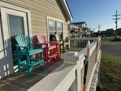 four colorful chairs on the porch of a house at Beautiful beach and bayfront house in North Topsail Beach
