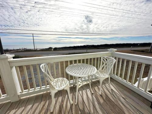 a table and chairs on a porch with a view of the ocean at Beautiful beach and bayfront house in North Topsail Beach