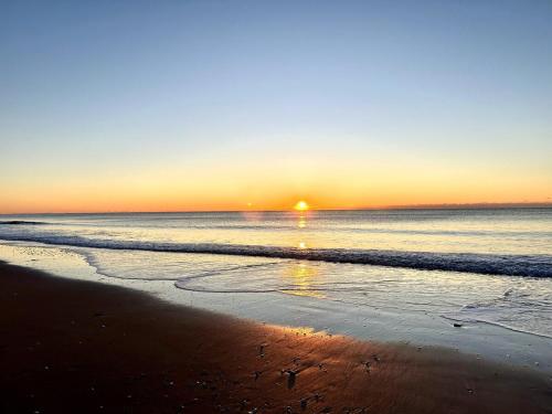 a sunset on a beach with the ocean at Beautiful beach and bayfront house in North Topsail Beach