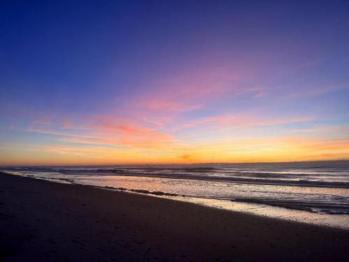 a sunset on a beach with the ocean at Beautiful beach and bayfront house in North Topsail Beach