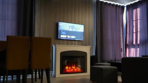 a living room with a fireplace with a tv above it at WoodNess Guest Hause in Tsaghkadzor