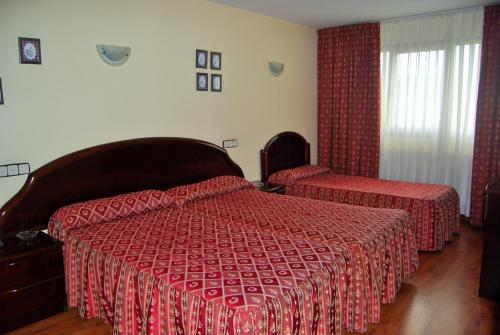 a bedroom with two beds with red comforter at Hotel Piedra in Perlora
