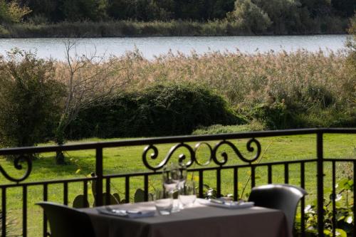 a table on a balcony with a view of a lake at Logis Hôtel Les Vieilles Granges in Granges-Les-Beaumont
