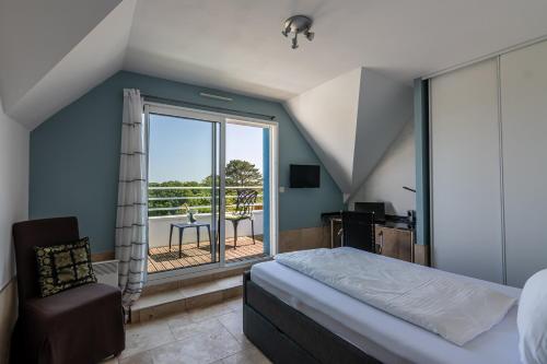 a bedroom with a bed and a window with a balcony at Villa DUXCAAR in Saint-Pabu