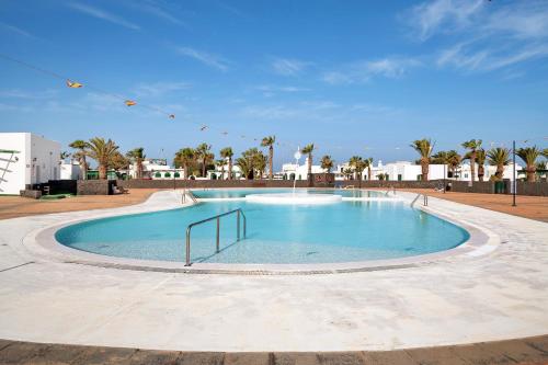 een groot zwembad in een resort met palmbomen bij El Palmeral in Playa Blanca