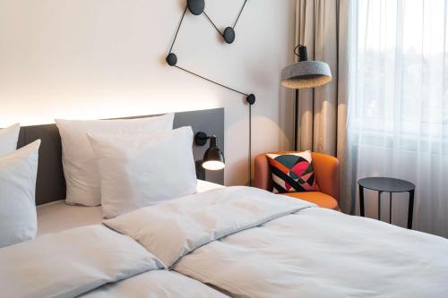 a bedroom with a white bed and a chair at Pentahotel Bremen in Bremen