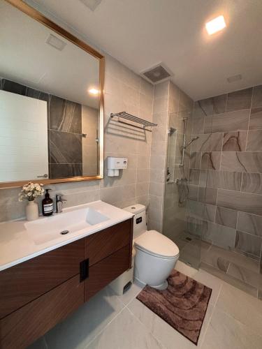 a bathroom with a toilet and a sink and a mirror at 2BR 4Beds Luxury Condo Pool & Fitness in Phuket