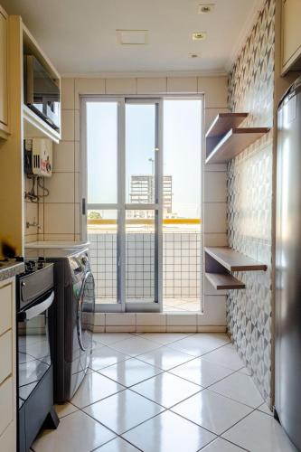 a kitchen with a large window and a tiled floor at Apartamento aconchegante em frente ao Shopping JL in Cascavel