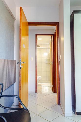 a hallway with a bathroom with a toilet and a chair at Apartamento aconchegante em frente ao Shopping JL in Cascavel