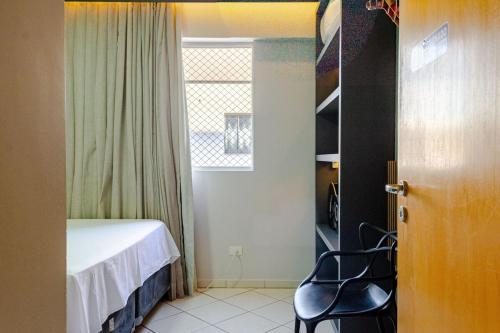 a bedroom with a bed and a chair next to a window at Apartamento aconchegante em frente ao Shopping JL in Cascavel