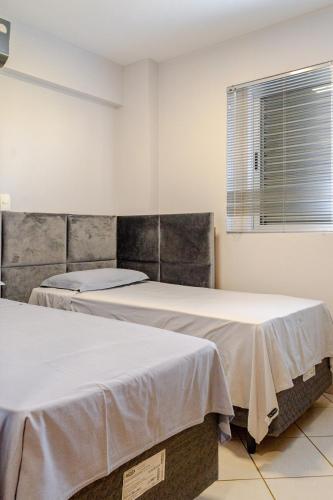 two beds sitting next to each other in a room at Apartamento aconchegante em frente ao Shopping JL in Cascavel