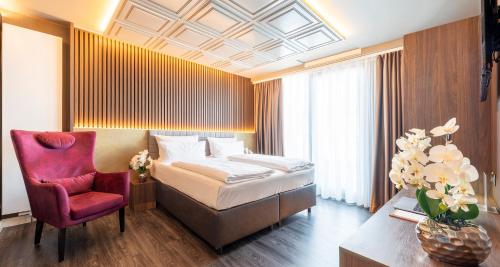 a hotel room with a bed and a red chair at PLAZA Premium Heidelberg in Heidelberg