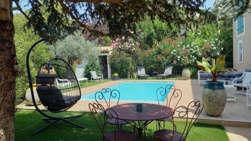 une cour avec une piscine, une table et une balançoire dans l'établissement Carry-le-Rouet, appartement 2 pièces, jardin et piscine, à Carry-le-Rouet