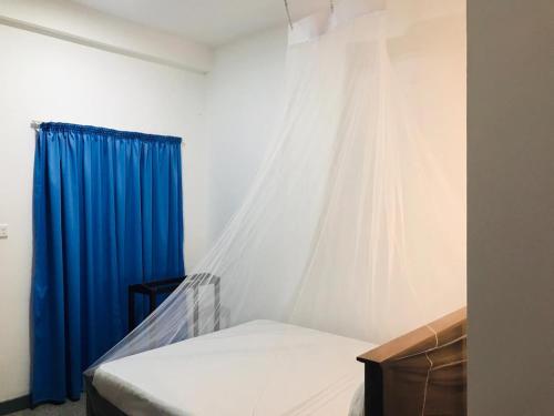 a bedroom with a bed with a blue curtain at Emerald Coast Hotel Negombo in Daluwekotuwa