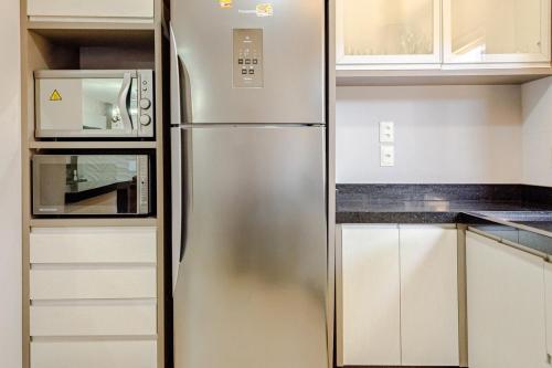 a stainless steel refrigerator in a kitchen with white cabinets at Casa ENORME, segurança e conforto para sua família in Cascavel