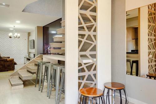 a kitchen with bar stools and a staircase in a house at Casa ENORME, segurança e conforto para sua família in Cascavel
