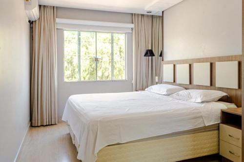a bedroom with a large white bed and a window at Casa ENORME, segurança e conforto para sua família in Cascavel