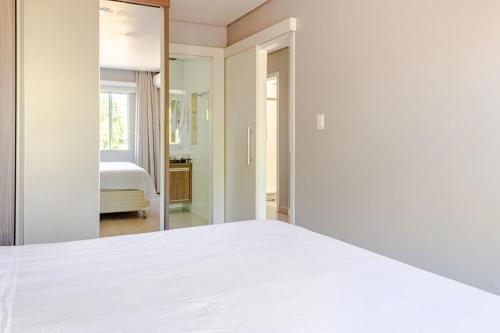 a bedroom with a white bed and a mirror at Casa ENORME, segurança e conforto para sua família in Cascavel