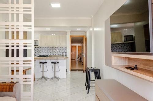 a kitchen with white cabinets and bar stools at Ótimo apartamento, em excelente localização JL Shopping in Cascavel