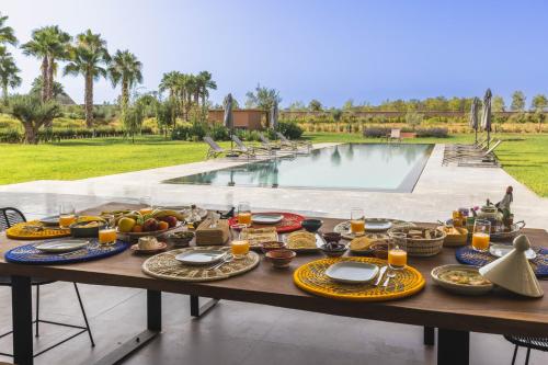 een tafel met eten erop naast een zwembad bij Villa Dar Tillili Marrakech in Heddad