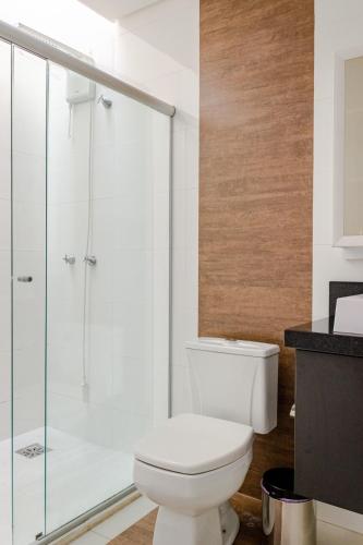 a bathroom with a toilet and a glass shower at Casa ENORME, segurança e conforto para sua família in Cascavel