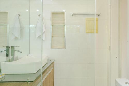 a white bathroom with a sink and a shower at Casa ENORME, segurança e conforto para sua família in Cascavel