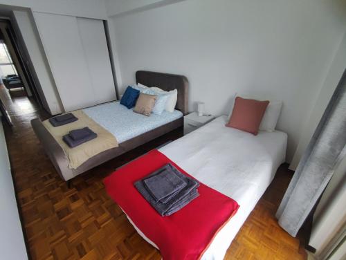 two beds in a small room with a red blanket at Lisbon spacious T2 in Damaia, Lisbon in Amadora